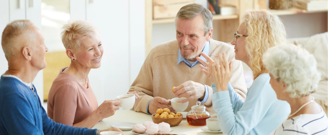 Ældre mennesker nyder en hyggelig kaffestund, symboliserende den omsorgsfulde service fra KBH Borydning inden for dødsborydning, rengøring af dødsbo og borydning af restbo