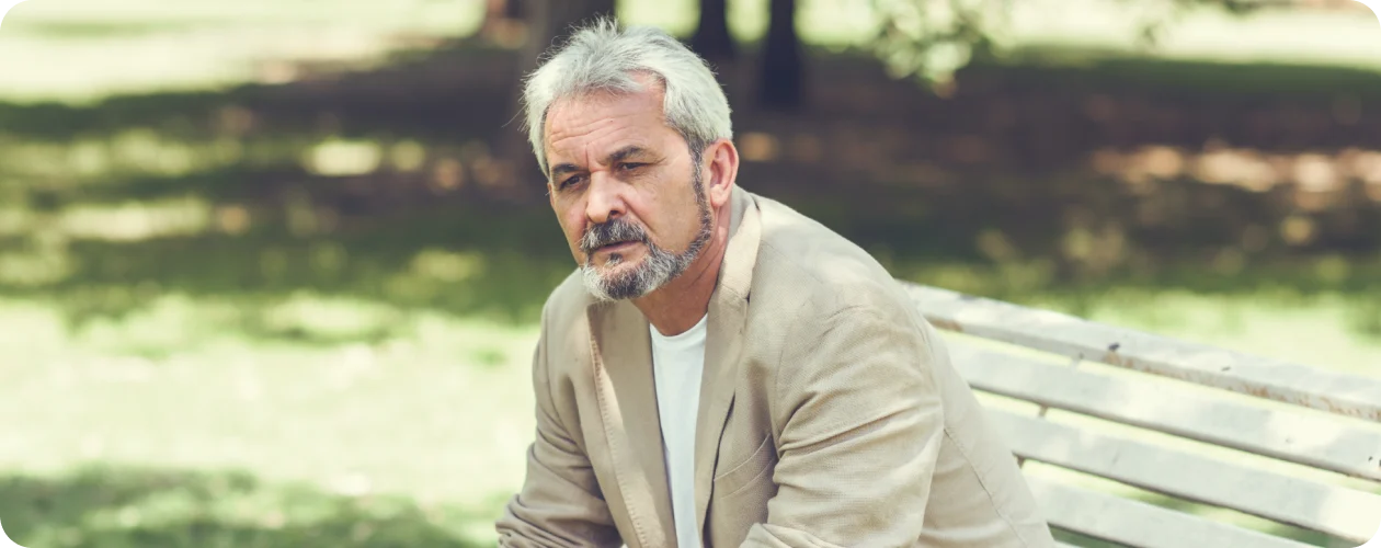 Ældre mand sidder tænksomt på en bænk, repræsenterer den følsomme støtte fra KBH Borydning ved dødsborydning.